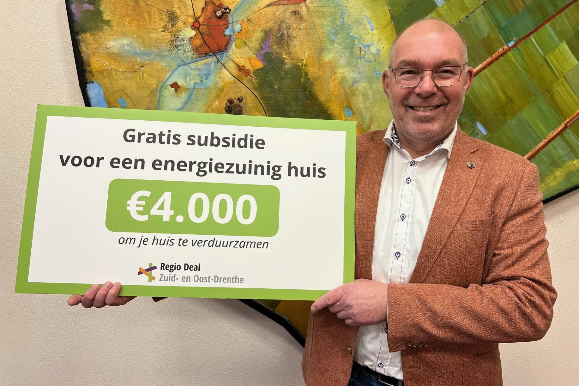 Wethouder Henk Zwiep toont cheque van 4.000 euro gratis subsidie voor energiezuinig huis